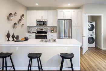 A kitchen with a white counter top with three stools